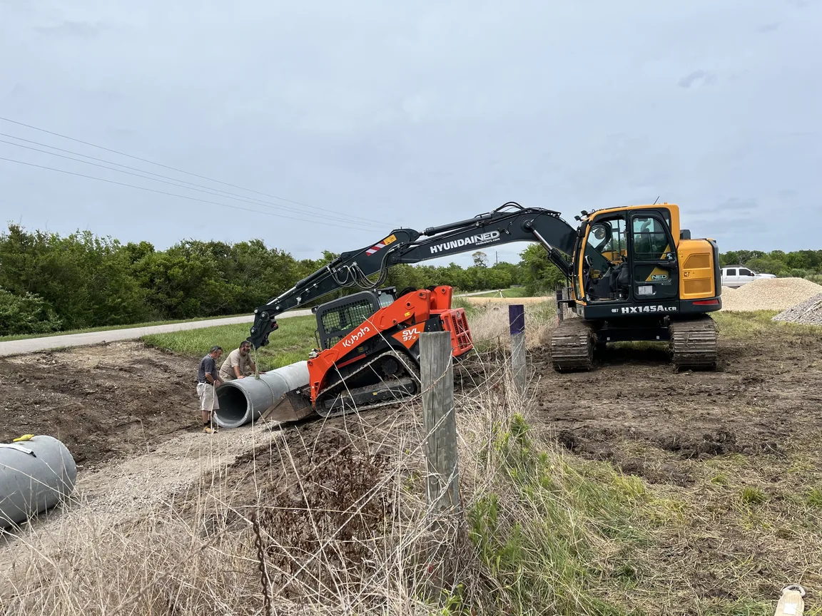 Excavator and skid steer setting a concrete culvert pipe, culvert installation
