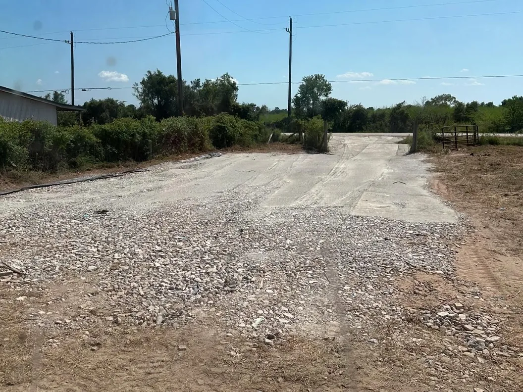Gravel drive and parking area spread at a property entrance, dirt work