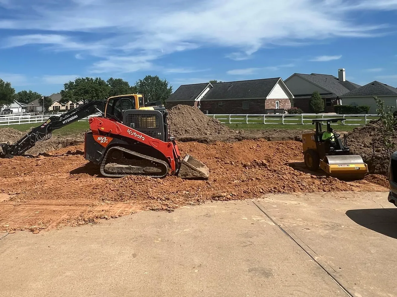 Skid steer, excavator and roller grading a building site, dirt work