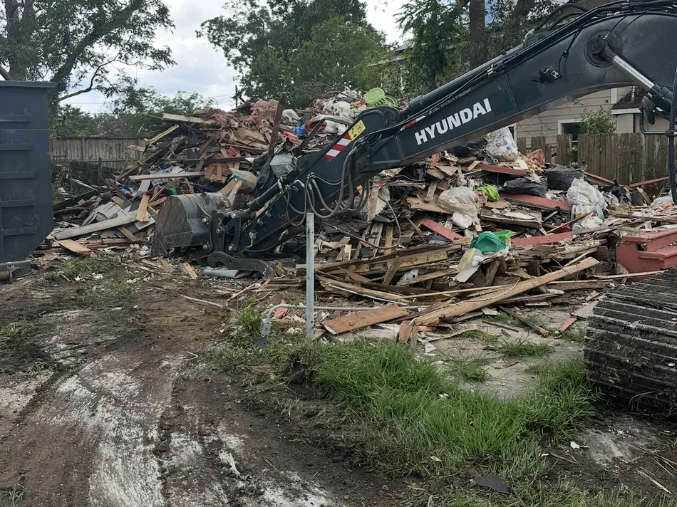 Excavator arm over a pile of house debris during cleanup, house demolition
