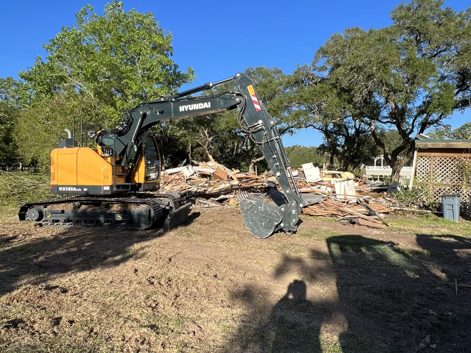 Excavator beside a pile of demolition debris, house demolition