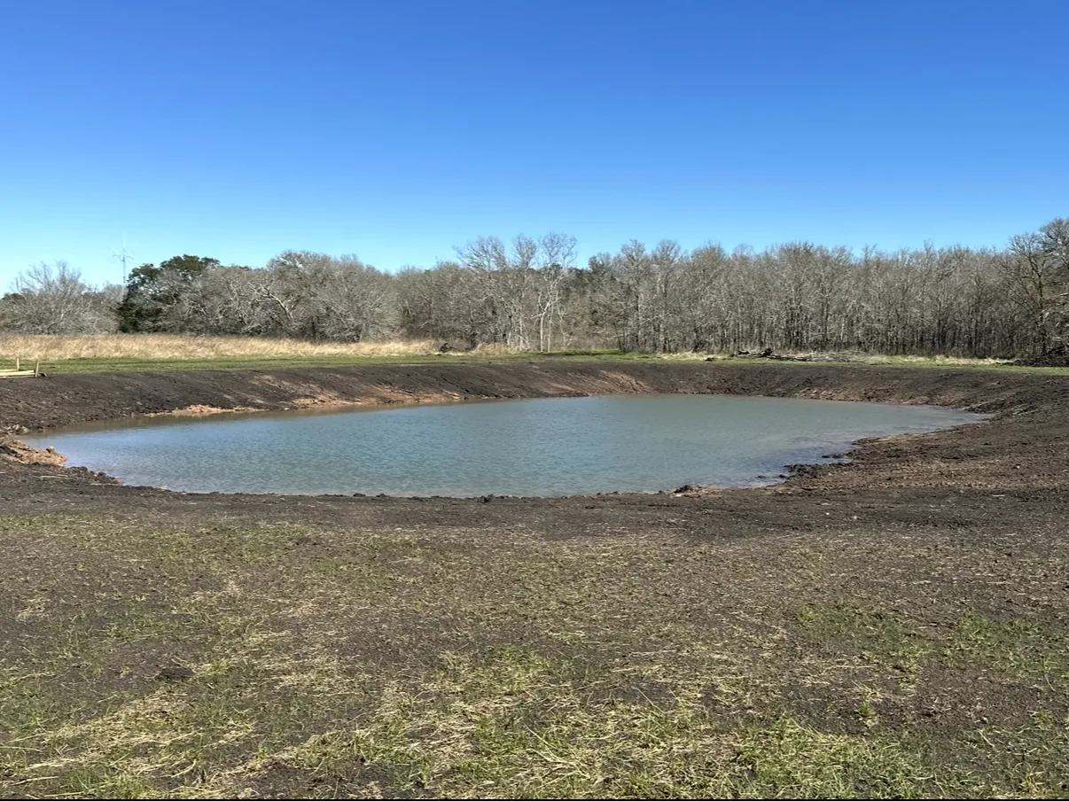 Expanded pond with smooth banks in an open field, pond construction