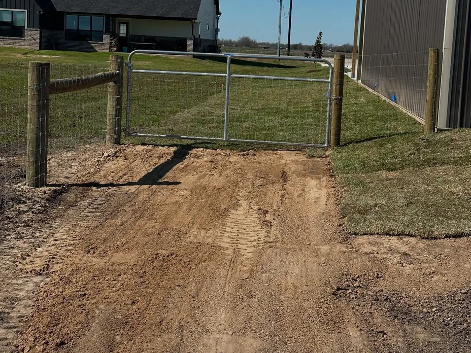 Metal ranch gate hung between wood posts on a new wire fence, ranch fencing