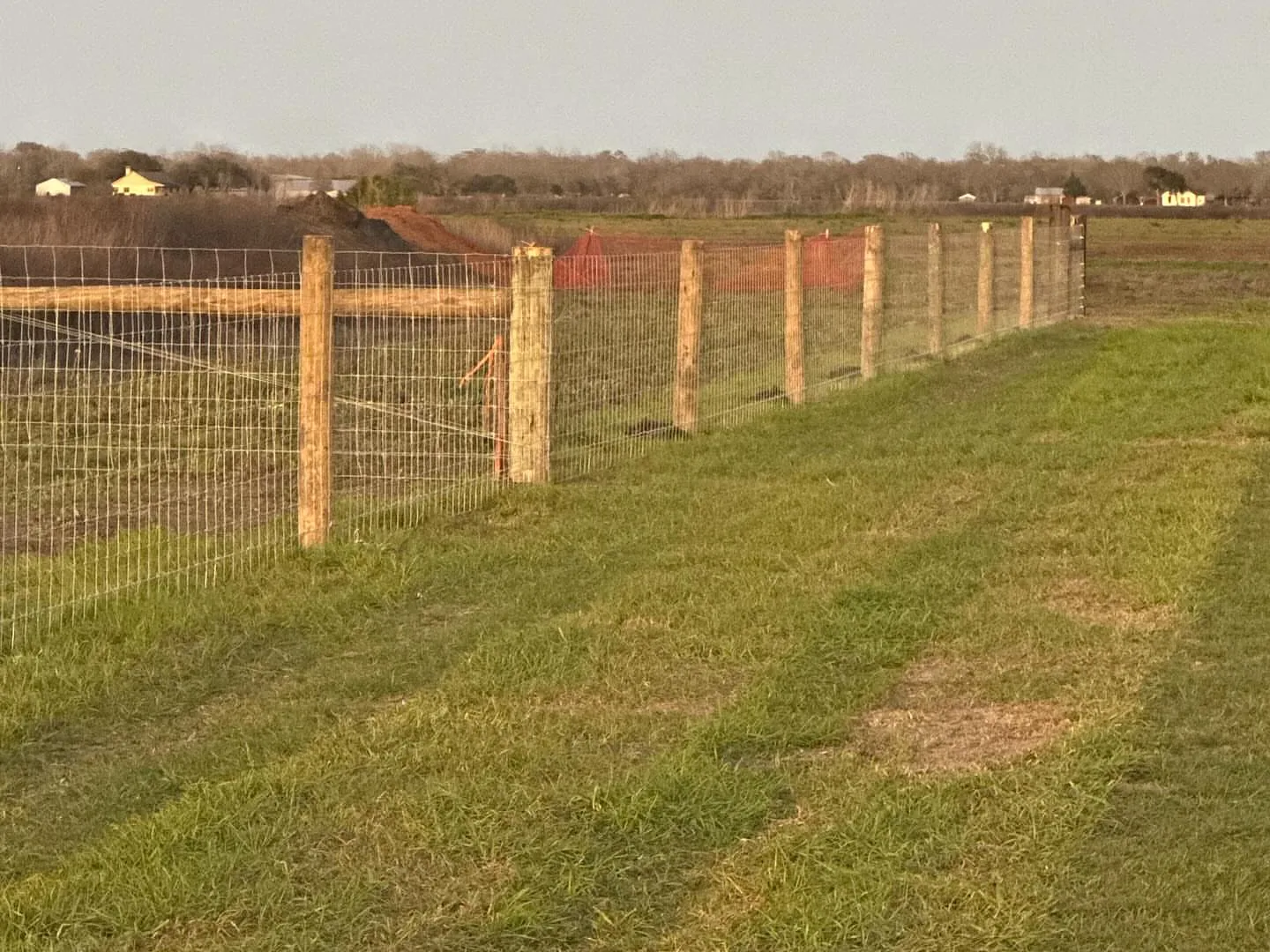 Woven wire fence on wood posts along a pasture, ranch fencing
